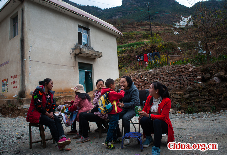 In a visit to local villagers, Doctor Ma Li plays with Guo Zhengpeng, a boy she delivered. [Photo by Pan Songgang/China.org.cn] 