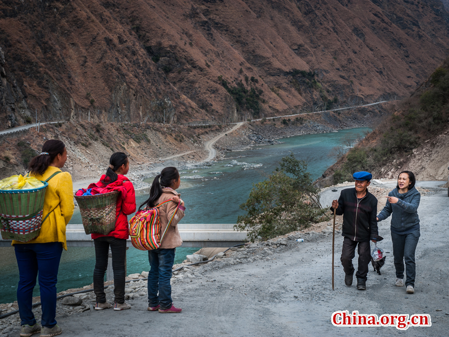 Local villagers warmly greet Ma Li who is helping a patient with difficulty walking on the way. [Photo by Pan Songgang/China.org.cn]