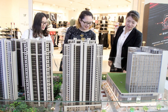 A representative of a real estate developer in Suzhou promotes an upcoming project to prospective buyers at a shopping mall, where a model of the property was kept on display at an industry event. [Photo/China Daily] 