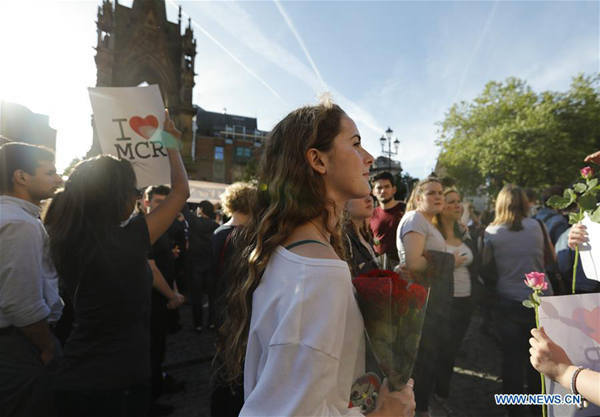 A young woman holds up roses during a candlelit vigil to mourn the victims of Manchester terror attack at Albert Square in Manchester, Britain on May 23, 2017. (Xinhua/Han Yan)