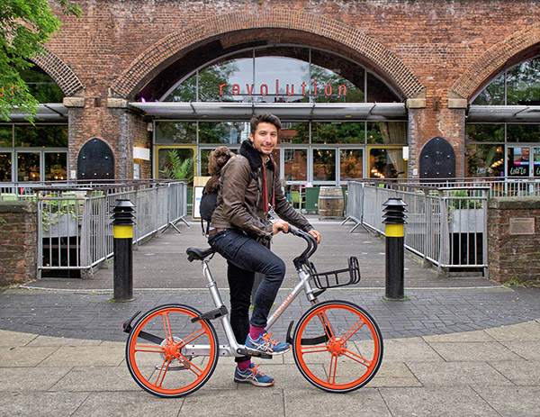 A cyclist tries Chinese bike-sharing company Mobike's new orange bike in Manchester. [Photo/chinadaily.com.cn] 