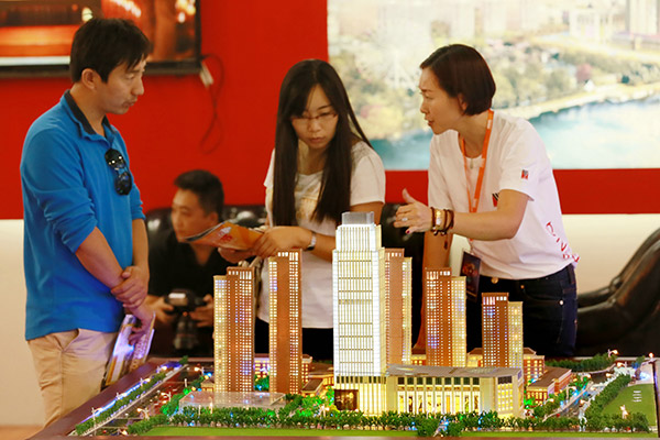 Prospective homebuyers enquire about an upcoming residential property at a Beijing real estate fair. Recent measures against speculative property investments are said to be pushing demand from top-tier cities to small cities. [Photo/China Daily] 
