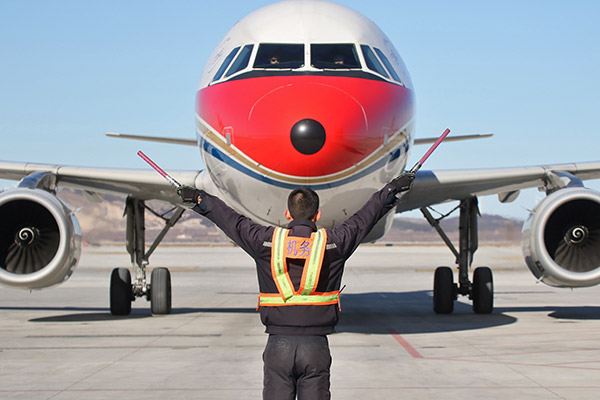 A ground crew member leads a China Eastern Airlines cargo plane to land at Yantai Penglai International Airport in Shandong province. [Photo/China Daily]