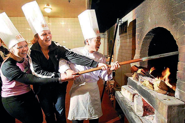 Tourists try their hand at making roast duck at the Quanjude Peking Roast Duck Restaurant’s Hepingmen branch.