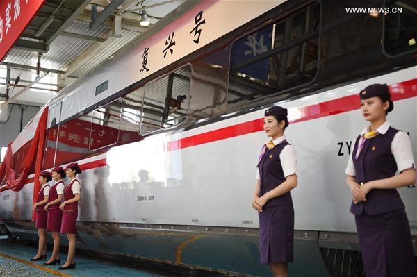 Crew members stand next to the CR400AF model of China's new electric multiple unit (EMU) train 'Fuxing' in Beijing, capital of China, June 25, 2017. China holds complete intellectual property rights of 'Fuxing' high speed trains. Two new 'Fuxing' trains will debut on Beijing-Shanghai high speed railway line on June 26, 2017 in Beijing and Shanghai at the same time. [Photo/Xinhua]