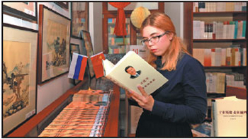 A Russian woman reads the Chinese version of Xi Jinping: The Governance of China on Monday at Chance Bookuu, a bookstore that sells Chinese books in central Moscow. ]Ren Qi / China Daily]