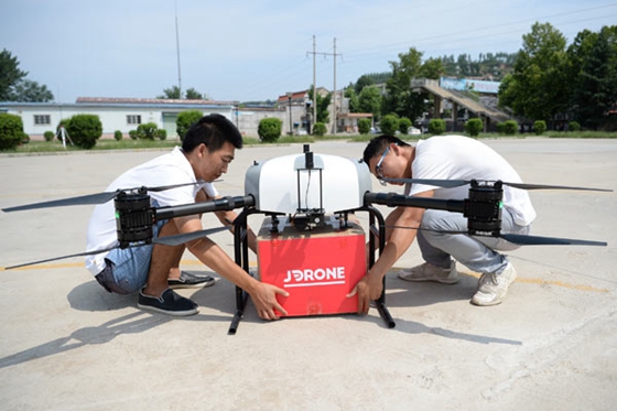 Staff from JD.com Inc attach a package to a drone in Xi&apos;an, capital of Shaanxi province. [Photo/Xinhua]