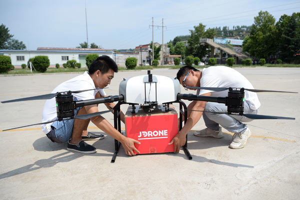 Staff from JD.com Inc attach a package to a drone in Xi'an, capital of Shaanxi province.
