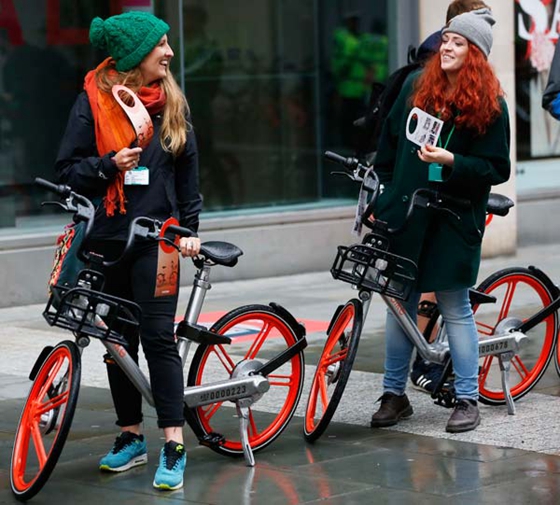 Two women ride Mobikes in Manchester in the United Kingdom. [Photo/Xinhua] 