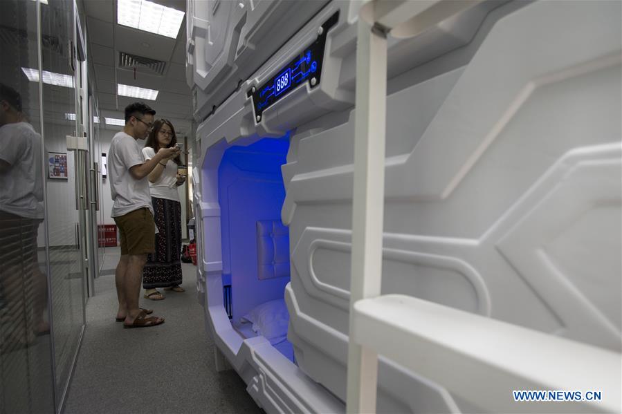 People learn how to use the shared compartment in Shanghai, east China, July 14, 2017. The shared compartment service appeared in some office buildings in Shanghai recently. People can enjoy a rest in the compartment by scanning the QR codes for payment. Disposable bedding is provided and the compartment will be disinfected automatically by ultraviolet light after use. [Photo/Xinhua]