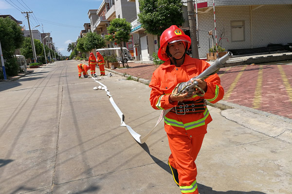 Wu Shuchun carries a firefighting hose at Shantou village, Dadeng Island in East China's Fujian province, on July 24, 2017. [Photo provided to chinadaily.com.cn]