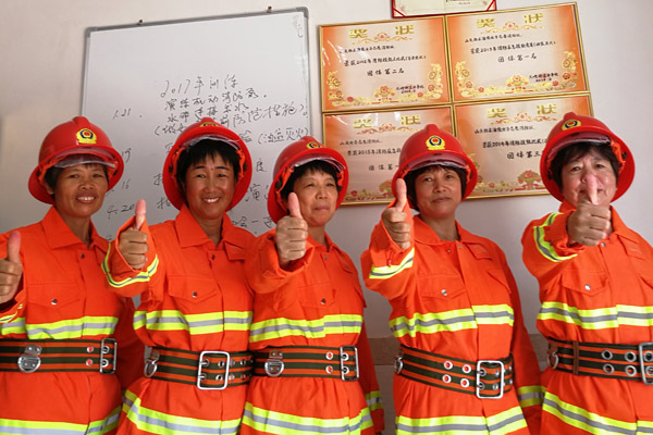 Wu Shuchun, 2nd from right, poses with other brigade members in front of the awards they've won in Shantou village, Dadeng Island in East China's Fujian province, on July 24, 2017. [Photo provided to chinadaily.com.cn]