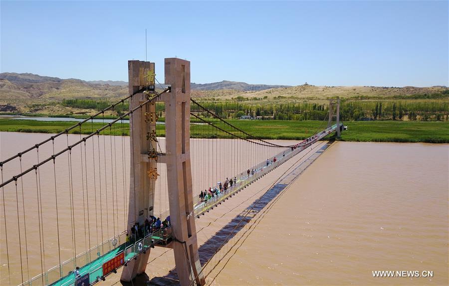 Tourists walk on a glass bridge across the Yellow River in Zhongwei, northwest China&apos;s Ningxia Hui Autonomous Region, Aug. 2, 2017. The 210-meter-long glass bridge was modified from an old suspension bridge by replacing the wooden deck with glass. (Xinhua/Li Ran)