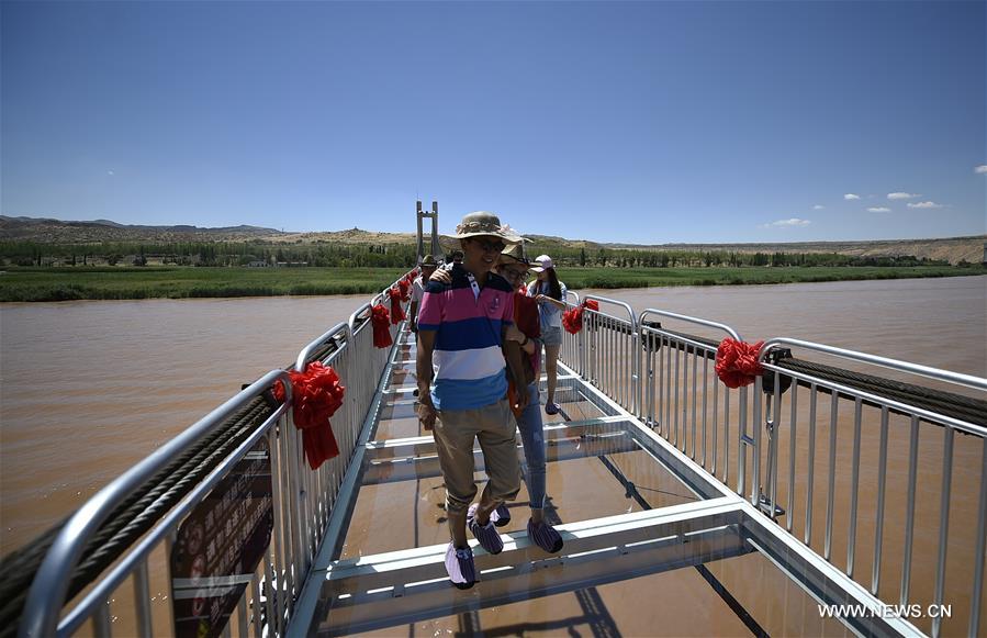 Tourists walk on a glass bridge across the Yellow River in Zhongwei, northwest China&apos;s Ningxia Hui Autonomous Region, Aug. 2, 2017. The 210-meter-long glass bridge was modified from an old suspension bridge by replacing the wooden deck with glass. (Xinhua/Li Ran) (zkr) 