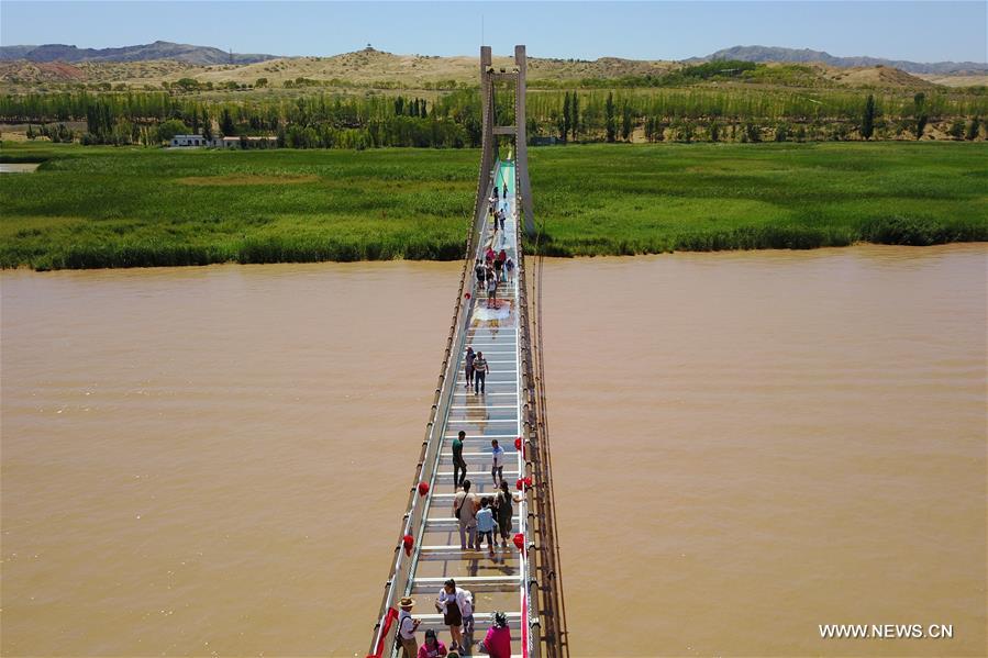 Tourists walk on a glass bridge across the Yellow River in Zhongwei, northwest China&apos;s Ningxia Hui Autonomous Region, Aug. 2, 2017. The 210-meter-long glass bridge was modified from an old suspension bridge by replacing the wooden deck with glass. (Xinhua/Li Ran) 