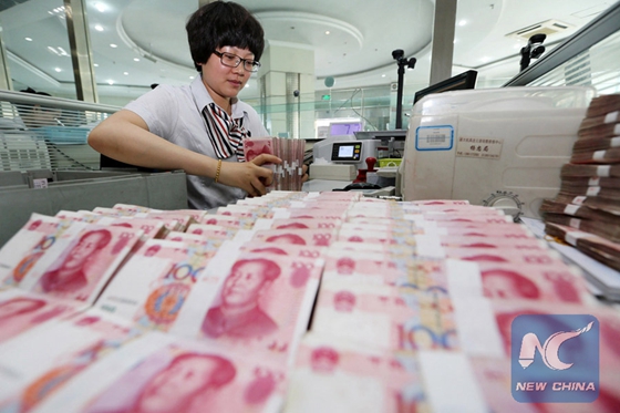 The file photo shows a bank employee arranges Chinese currency Renminbi (RMB). [Photo/Xinhua]