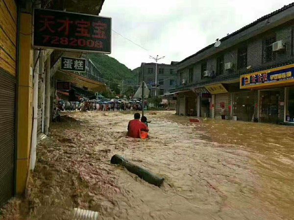 Liu Hongbo tries to help a shopkeeper when severe rainstorm hits Zhangguying county in Yueyang, Hunan province, Aug 12, 2017. [Photo provided to chinadaily.com.cn] 