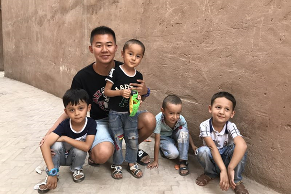 Liu Tongfeng poses with local kids for a photo during his trip. [Photo provided to chinadaily.com.cn] 