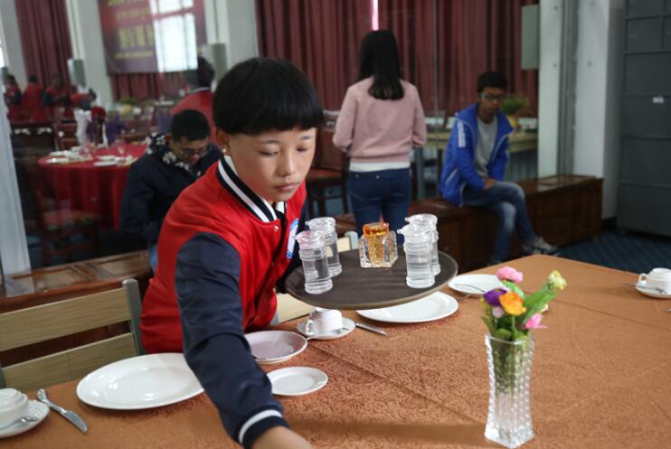 Zhaxi Ciyang, a second-year student of high-end catering services major in the Second Middle Vocational School of Lhasa lays out the table in Western style in a model training workshop of her school. [Photo / China.org.cn]