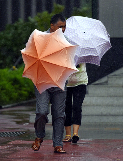 Pedestrians brave Typhoon Pakhar's strong winds and rain in Shenzhen, Guangdong province, on Sunday. [Photo/Xinhua]