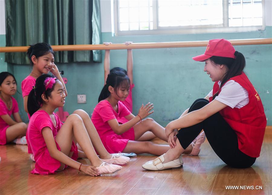 A volunteer from a charity group talks with dance troupe members in the Red Army Primary School in Liangnong Town of Yuyao City, east China's Zhejiang Province, Sept. 1, 2017.