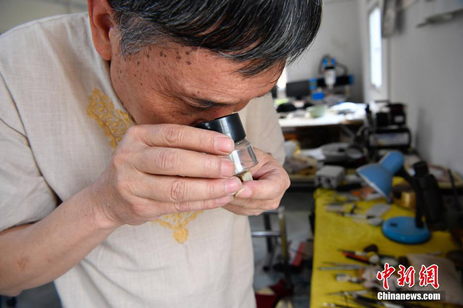 n Longquan, a master of microscopic carving, scrutinizes his works at his studio in Kunming, southwestern China's Yunnan province, Sept 12, 2017. [Photo/Chinanews.com] 