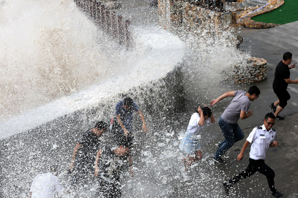 A wave crashes into a barrier in Wenling, Zhejiang province, on Thursday ahead of Typhoon Talim. [Photo/China Daily]
