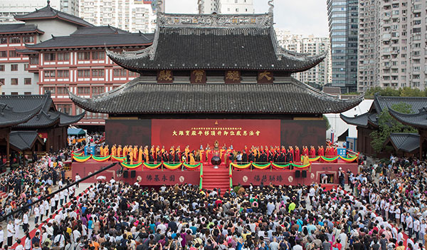 Tourists and monks attend a ceremony of gratitude at the Grand Hall of the Jade Buddha Temple in Shanghai on Sunday. The hall was moved 31 meters north and raised 1 meter. [Gao Erqiang/China Daily]