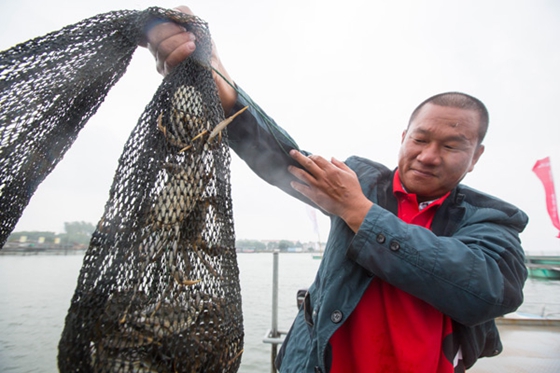 A fisherman with a net of hairy crabs at Yangcheng Lake, Suzhou, East China's Jiangsu Province. [Photo/China Daily]