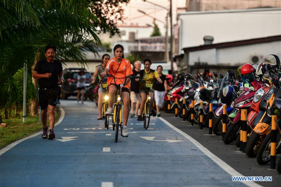 Local residents ride ofo sharing-bikes on a bike lane at a public park in Phuket, Thailand, Oct. 5, 2017. China's dock-less bike-sharing company ofo provided more than 1,000 bikes in Phuket's key locations in late September and offered a 1-month free trial without deposit fee. Now the bike-sharing service has benefited local residents and tourists. Ofo's regular service fee will be charged at 5 Baht per 30 minutes usage, with a deposit fee of 99 Baht. [Photo/Xinhua]