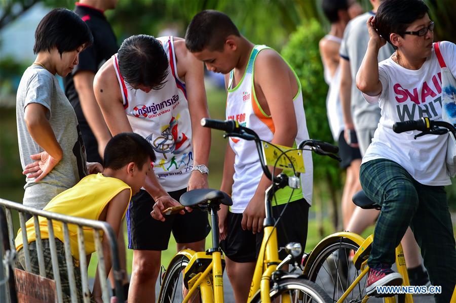 A local resident unlocks an ofo sharing-bike by scanning the QR code at a public park in Phuket, Thailand, Oct. 5, 2017. China's dock-less bike-sharing company ofo provided more than 1,000 bikes in Phuket's key locations in late September and offered a 1-month free trial without deposit fee. Now the bike-sharing service has benefited local residents and tourists. Ofo's regular service fee will be charged at 5 Baht per 30 minutes usage, with a deposit fee of 99 Baht. [Photo/Xinhua]