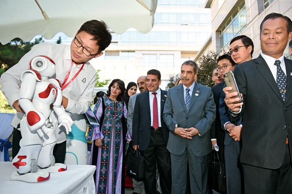 Tawfiq al-Tirawi (fifth from right), a member of the Palestinian Fatah Central Committee, and other foreign guests learn more about the robot developed by a Hubei-based company at a thematic briefing event on the supply-side structural reform in Beijing on May 25.