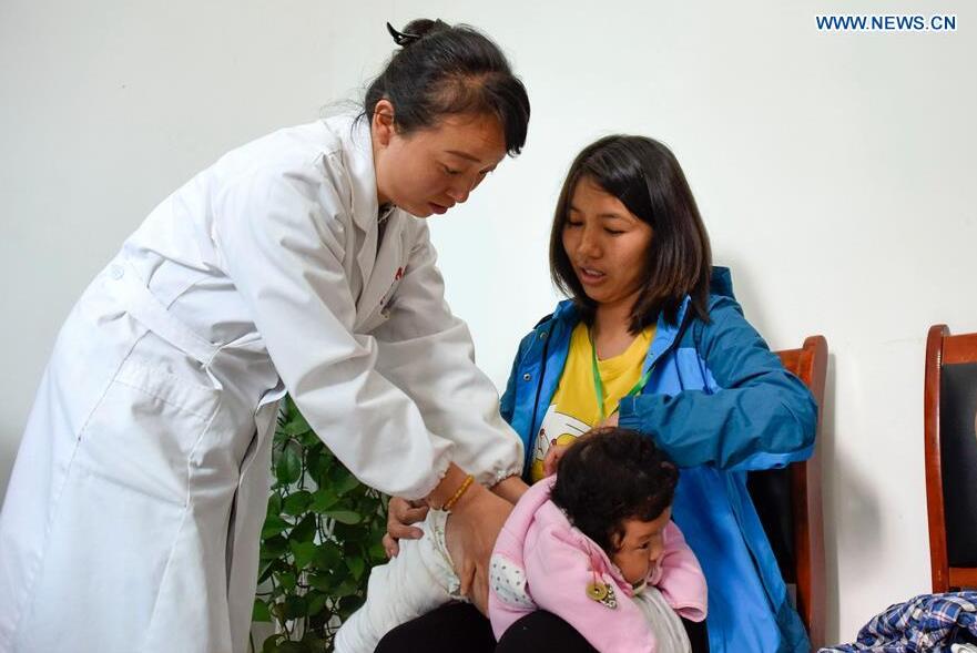 Zhong Jing (L), a doctor of Longhe Village clinic, examines a patient in Zhenfeng County, southwest China's Guizhou Province, Oct. 11, 2017. 