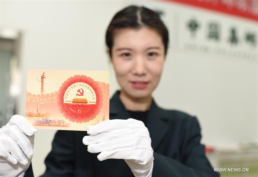 A postal staff member shows a stamp sheetlet in Hengshui, north China&apos;s Hebei Province, Oct. 18, 2017. China Post issued a set of commemorative stamps marking the 19th National Congress of the Communist Party of China on Wednesday. The set consists of two stamps and a stamp sheetlet. (Xinhua/Zhu Xudong)