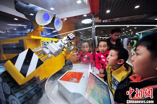 This undated photo shows students are attracted by a robot exhibited in Shenyang, capital of northeast China's Liaoning Province. [File photo/China News Service]