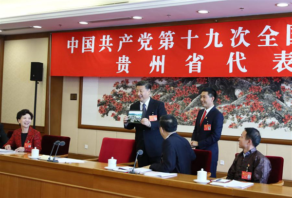 Xi Jinping praises a photo for the beautiful scenery of Huamao Village in Guizhou Province when receiving it from Pan Kegang, Party secretary of the village, during a panel discussion with delegates from Guizhou at the 19th National Congress of the Communist Party of China in Beijing, Oct. 19, 2017. (Xinhua/Lan Hongguang)