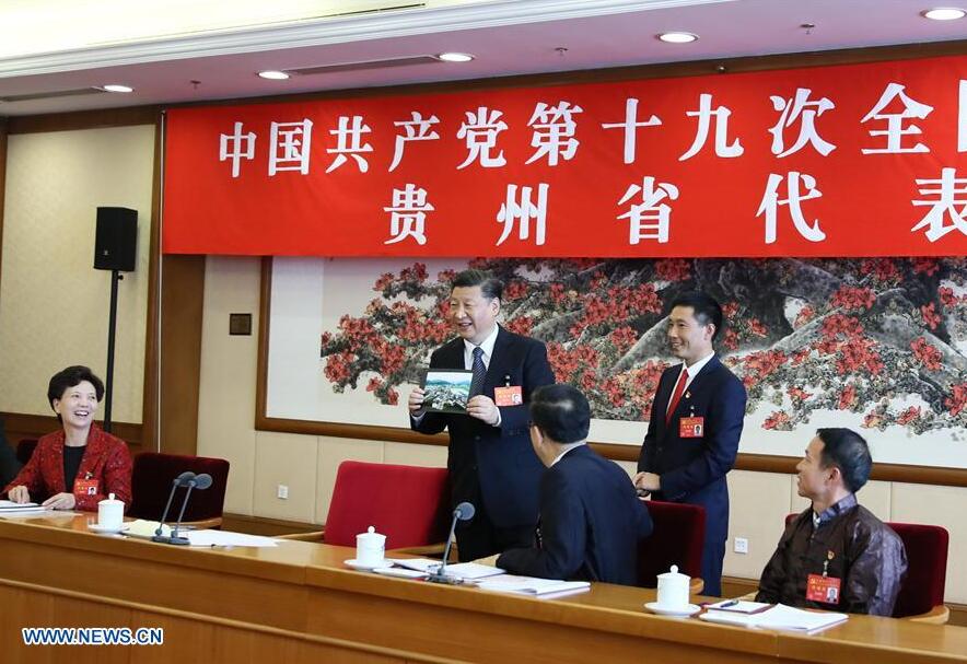 Xi Jinping praises a photo for the beautiful scenery of Huamao Village in Guizhou Province when receiving it from Pan Kegang, Party secretary of the village, during a panel discussion with delegates from Guizhou at the 19th National Congress of the Communist Party of China in Beijing, Oct. 19, 2017. (Xinhua/Lan Hongguang) 