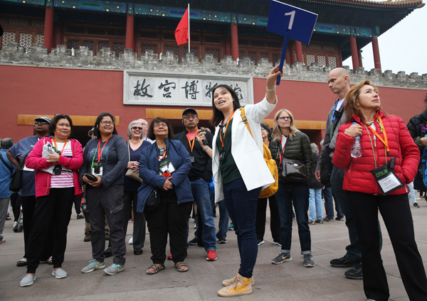 A guide shows a group of tourists around the Palace Museum in Beijing in October. [Photo/China Daily] 