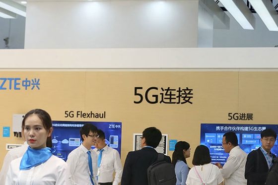 Visitors check information about 5G services at the booth of ZTE Corp at the PT/Expo China 2017 in Beijing. [Photo/China Daily]