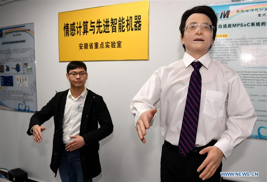 A researcher (L) and robot Xiang Xiang conduct synchronous interaction at Hefei University of Technology in Hefei, capital of east China&apos;s Anhui Province, Nov. 16, 2017. Robots Si Si and Xiang Xiang, developed by the university, have the initial abilities of making conversations and synchronous interaction with humans. (Xinhua/Liu Junxi) 