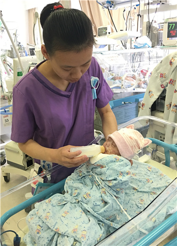 A nurse feeds a newborn baby at Children's Hospital of Fudan University in Shanghai earlier this month. [Provided to China Daily]