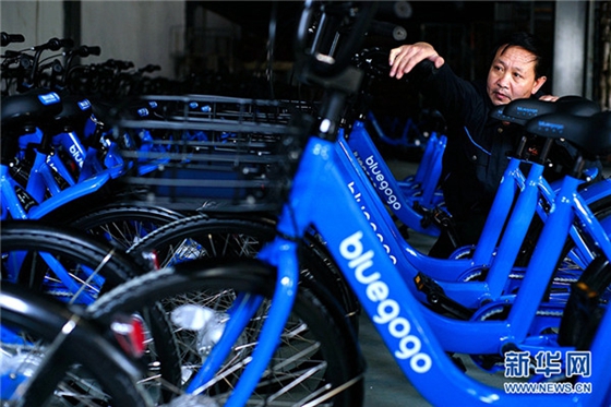 A staff member examines the newly manufactured bluegogo bikes. [Photo/Xinhua]