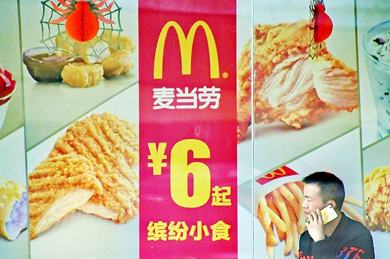 A pedestrian passes an advertisement for McDonald's in Zhengzhou, capital of Henan province. [Photo/China Daily] 