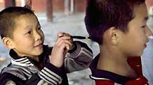 He Minxian (L), a 9-year-old kid, makes a braid for a classmate in the Shaolin Tagou Kung Fu (Martial Art) Institute at the foot of Mountain Song in Dengfeng, a city of central China's Henan Province, October 12, 2009.