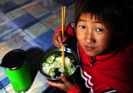 A boy eats on the campus of the Orphanage School for Ethnic Minorities in Lijiang, southwest China's Yunnan Province, October 24, 2009.