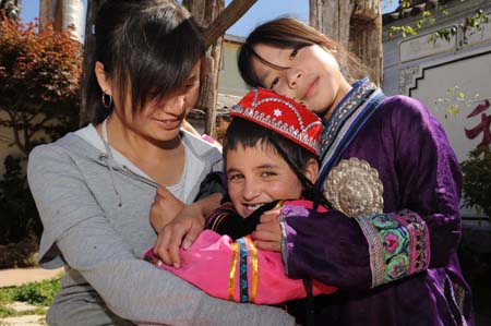 Teacher Yang Li (L) cuddles a Tajik little girl in bosom on the campus of the Orphanage School for Ethnic Minorities in Lijiang, southwest China's Yunnan Province, October 24, 2009.