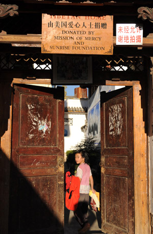 A girl turns round his head upon her entry into the dormitory gate on the campus of the Orphanage School for Ethnic Minorities in Lijiang, southwest China's Yunnan Province, October 28, 2009.