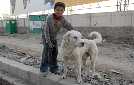 Rueid plays with his dog at his roadside workshop in Kabul, capital of Afghanistan, on October 24, 2009.