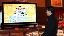 A man watches the Universal Children's Day report covered by Xinhua News Agency in a hotel in Brussels, capital of Belgium, November 19, 2009.
