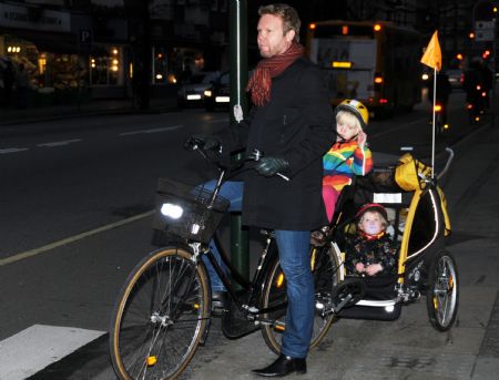 A bicycler taking his children waits to cross a street in Copenhagen, capital of Denmark, on November 23, 2009.